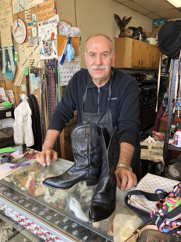 George behind his glass counter, presenting a pair of finished black cowboy boots