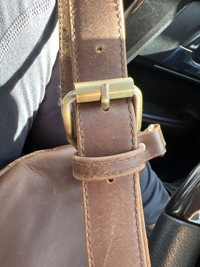 A leather belt with a brass buckle on the workbench