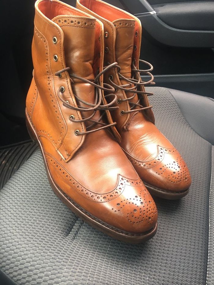 A pair of tan brogue boots after repair, laced and polished