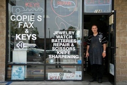 George standing in the doorway of his shop, under the suite 108 sign, with neon repair signs in the windows