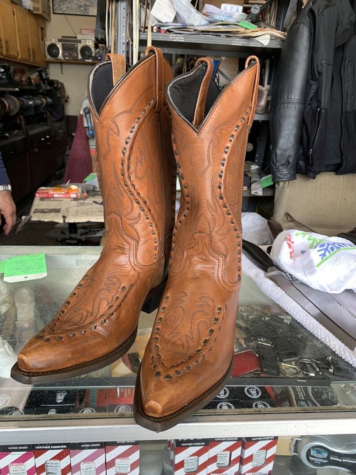 Tan wingtip cowboy boots standing on the counter after repair
